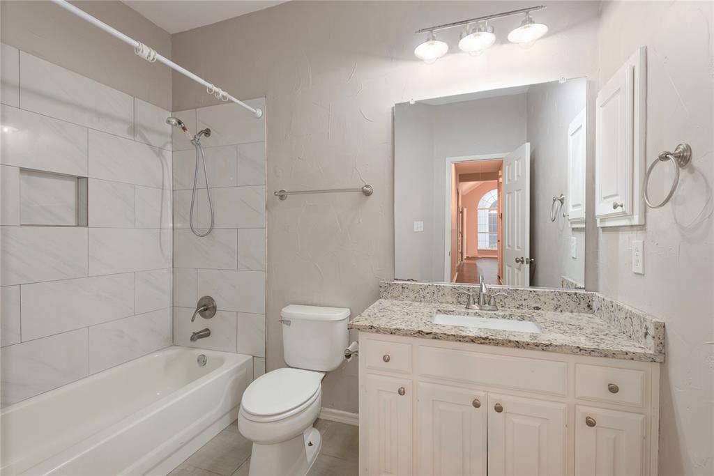 7829 Case Drive, Plano, TX 75025 Full bathroom featuring tile patterned flooring, tiled shower / bath combo, toilet, and vanity
