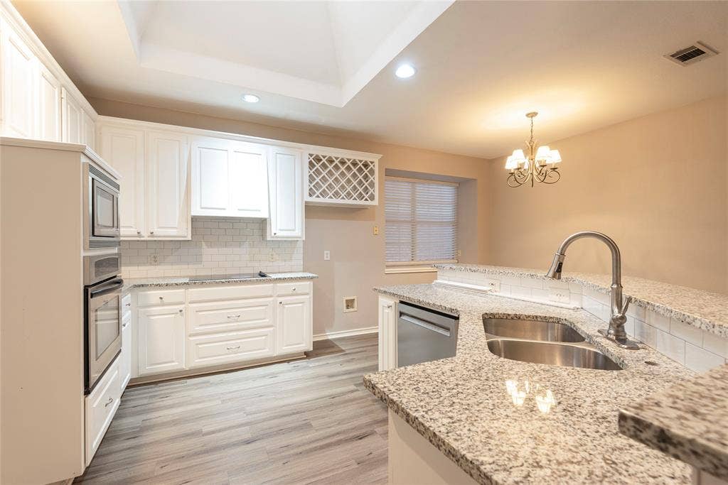 7829 Case Drive, Plano, TX 75025 Kitchen with pendant lighting, white cabinets, sink, light stone counters, and stainless steel appliances