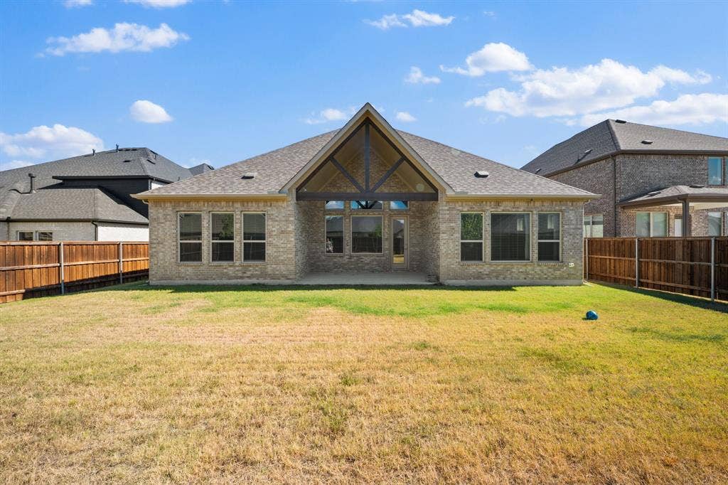 Rear exterior featuring a covered patio, brick facade, and a gabled roofline with exposed wood beams
