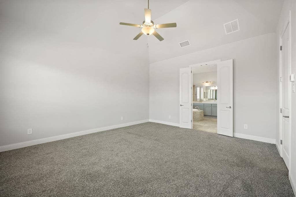 Vaulted ceiling with a ceiling fan, plush gray carpet, and double entry doors