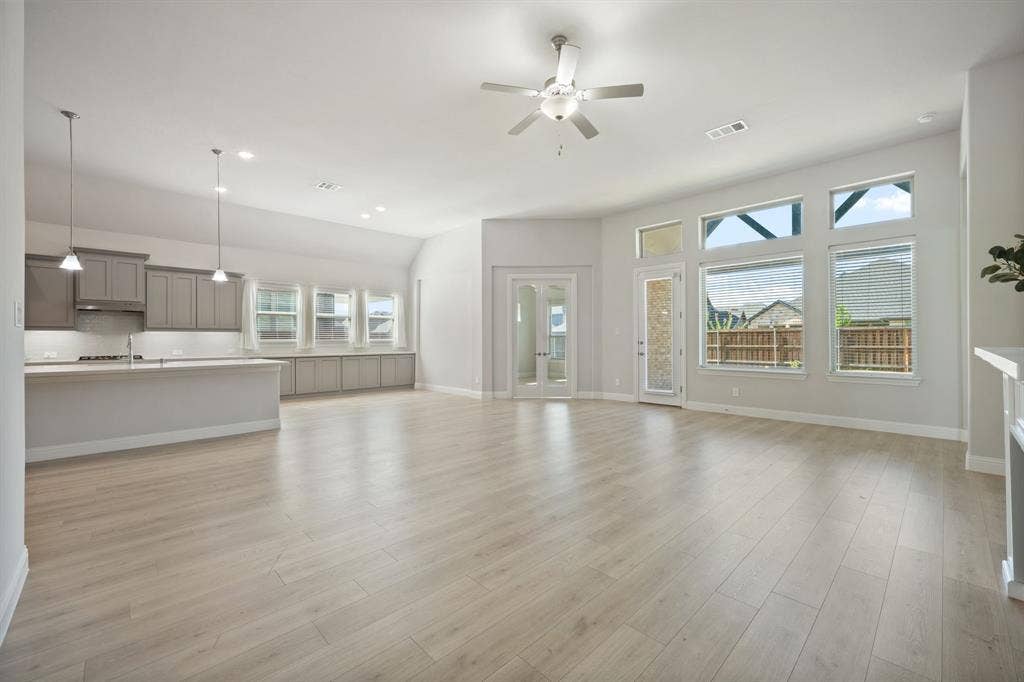 Vaulted ceiling with a ceiling fan, light wood-finish flooring, recessed lighting, and a kitchen featuring gray cabinetry and a peninsula