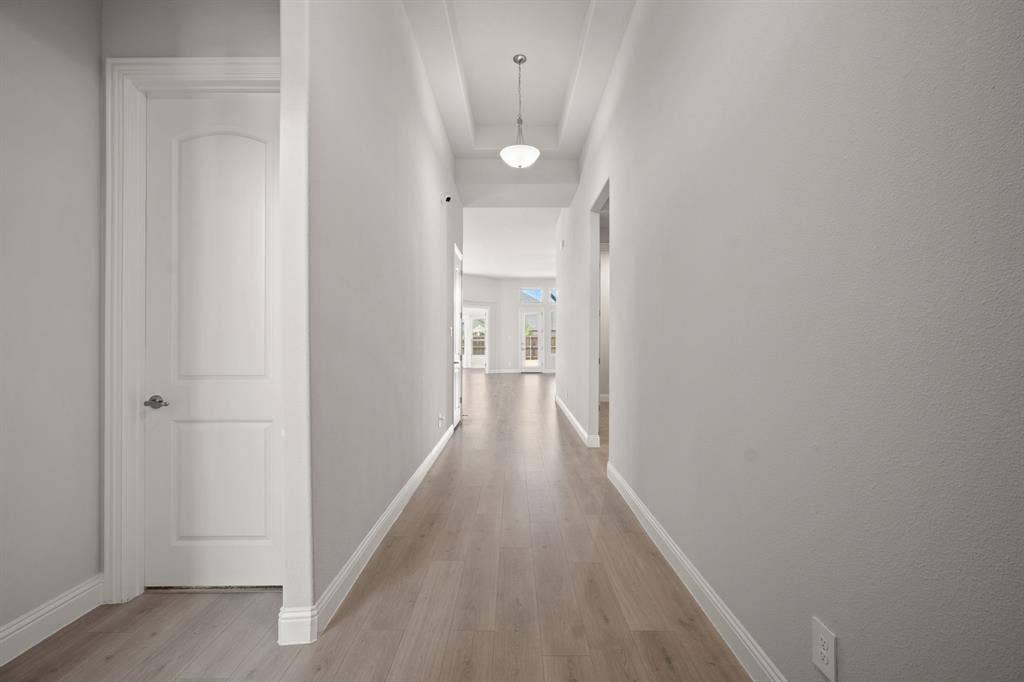 Hallway featuring light wood-finish flooring, a coffered ceiling, and a flush-mount light fixture