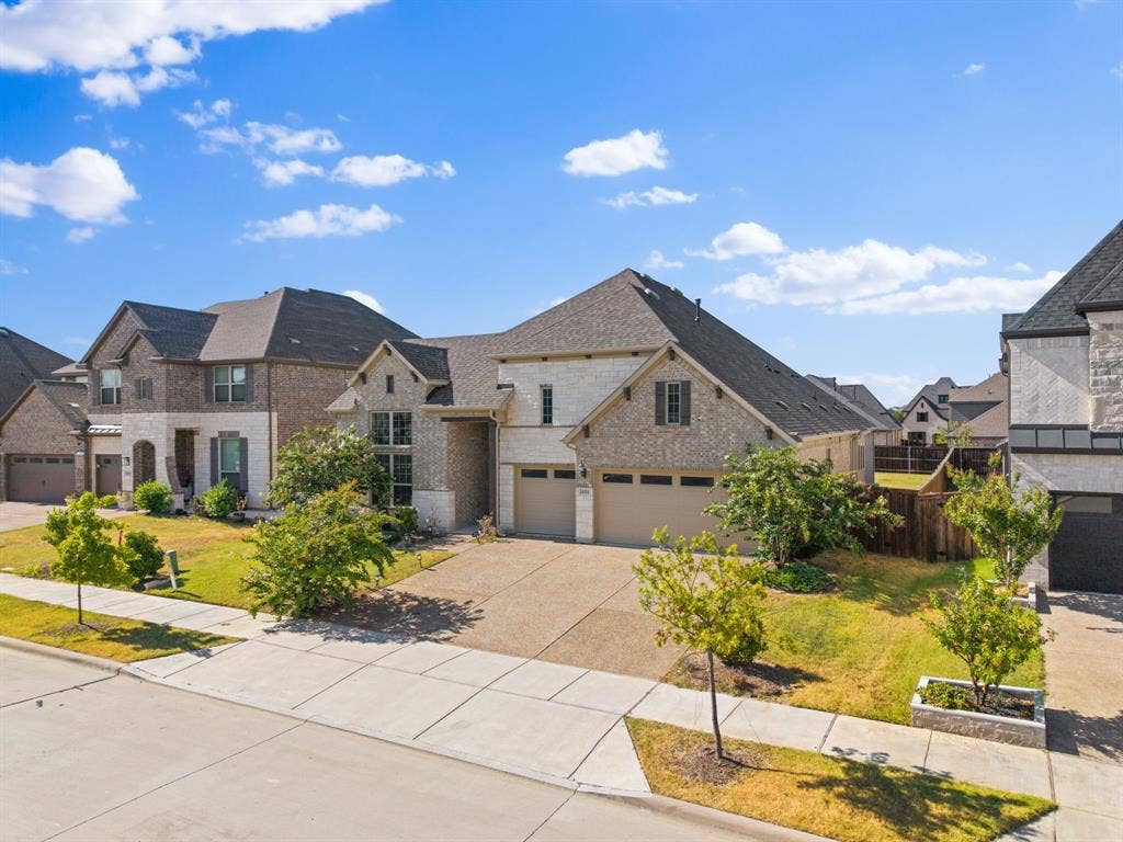 Stone and brick exterior with a multi-car driveway, two-car garage, and established landscaping