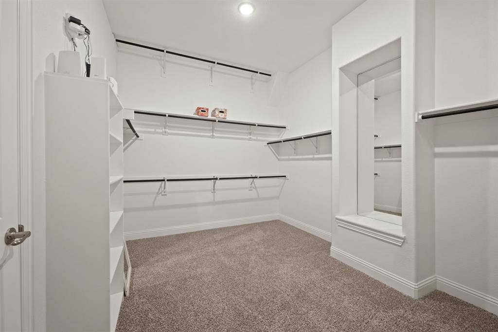 Built-in open shelving and hanging rods, recessed ceiling lighting, and soft carpet flooring