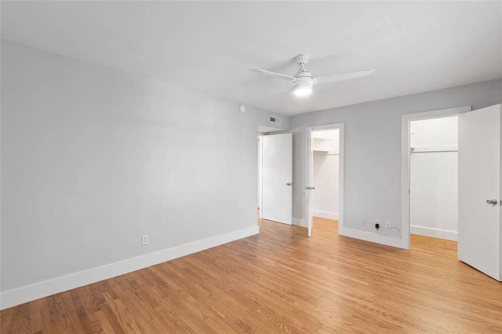 Unfurnished bedroom with a spacious closet, light wood-style flooring, and ceiling fan