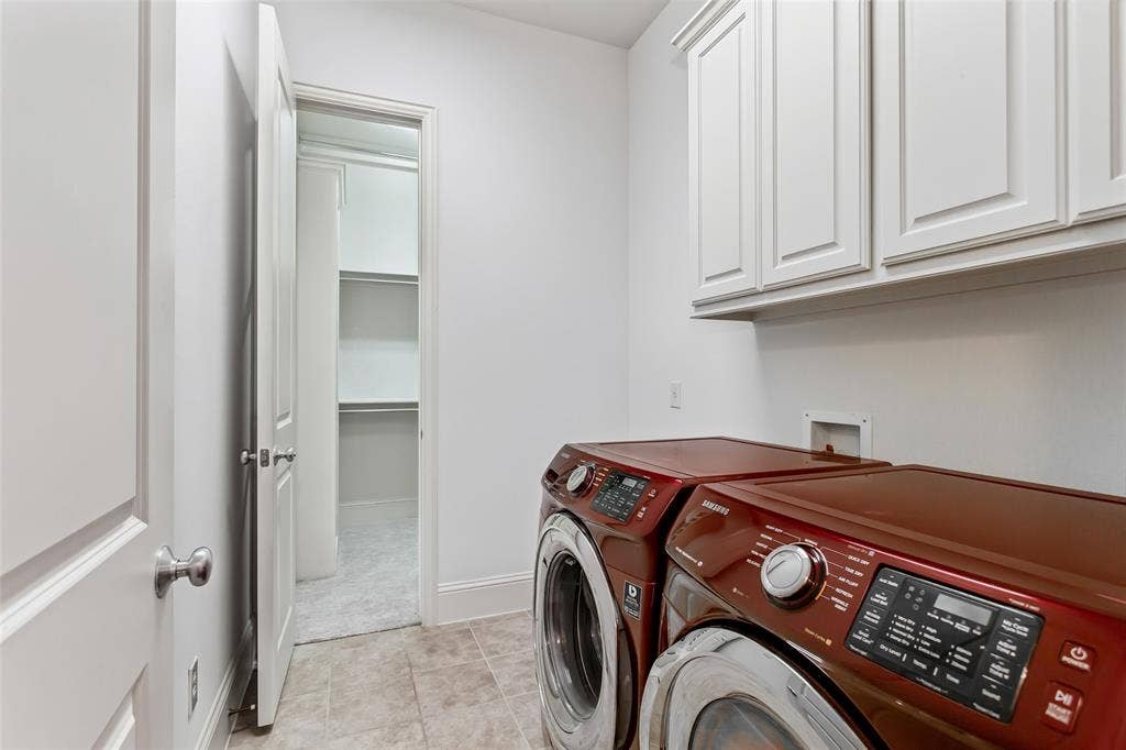 Laundry area with white upper cabinetry, tiled flooring, and an adjoining closet with built-in shelving