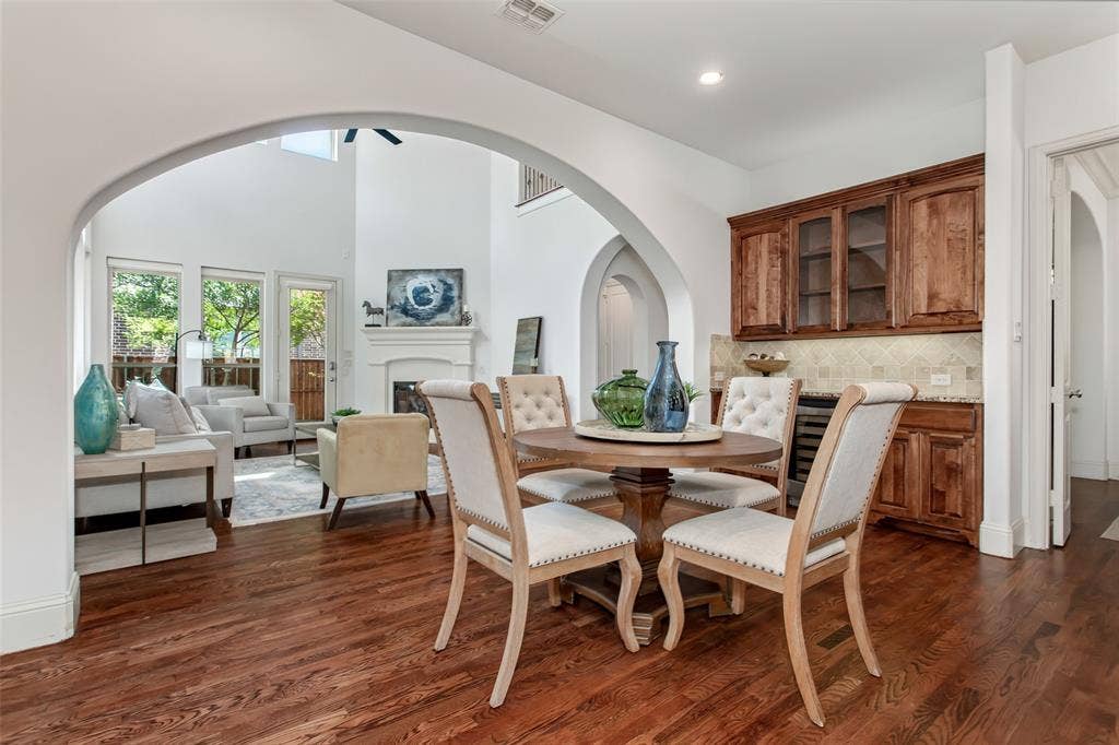Arched entryways, wood-finish flooring, built-in wet bar with cabinetry, and a fireplace in the living area