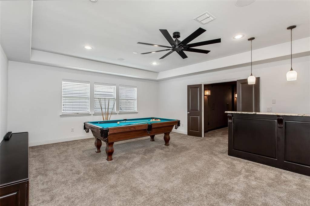 Recessed lighting, ceiling fan, tray ceiling, triple windows, and a built-in bar with pendant lighting