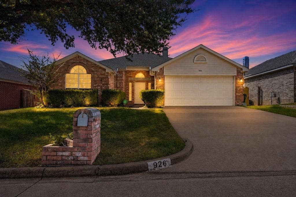 926 Wintercrest Court, Arlington, TX 76017 Brick and siding exterior with an arched window, attached two-car garage, concrete driveway, and mature landscaping