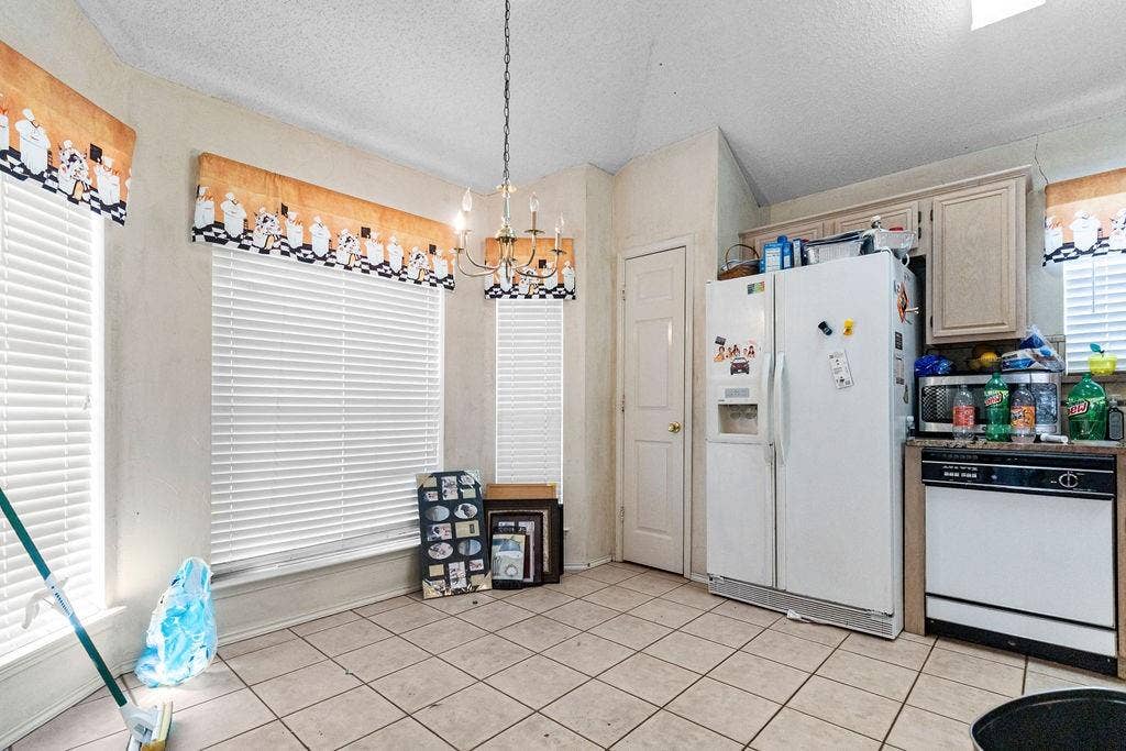 926 Wintercrest Court, Arlington, TX 76017 Tiled flooring with a multi-light chandelier, a white side-by-side refrigerator, and upper cabinetry