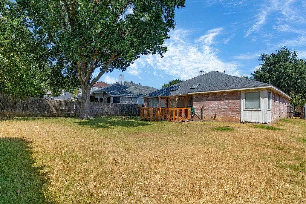 926 Wintercrest Court, Arlington, TX 76017 Expansive backyard featuring a mature shade tree, privacy fencing, and a wood deck