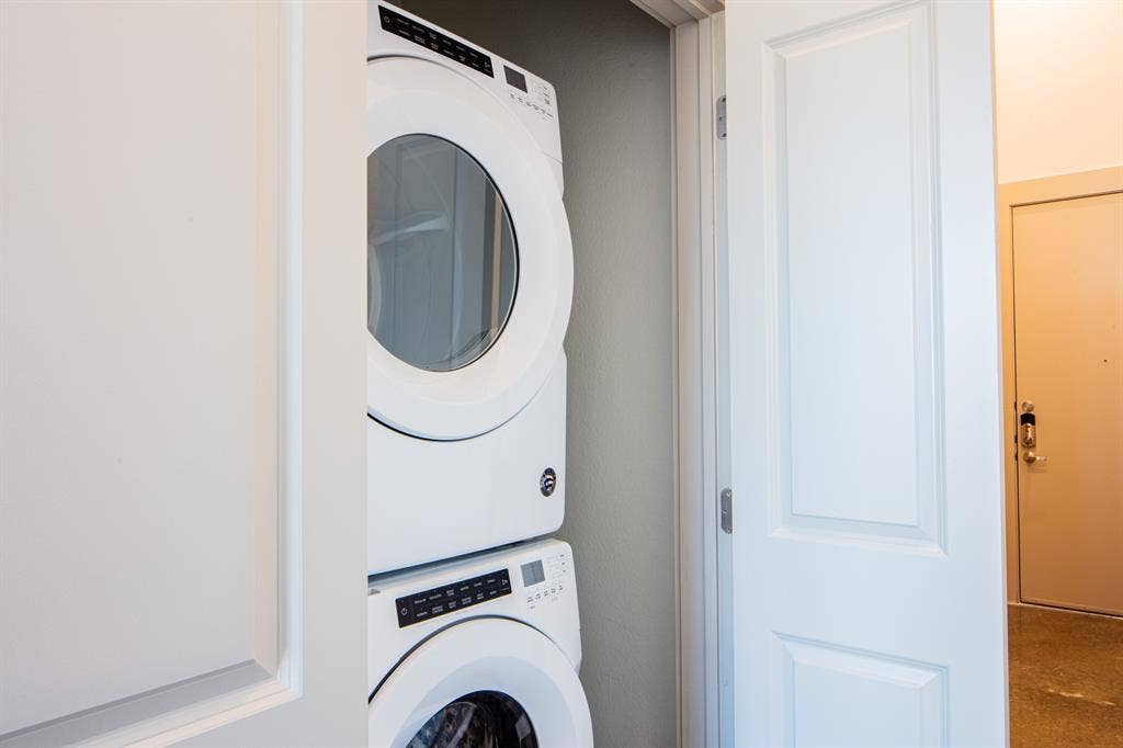 830 N Zang Boulevard, #1317, Dallas, TX 75208 Clothes washing area featuring stacked washing maching and dryer