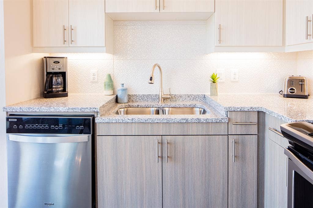 830 N Zang Boulevard, #1317, Dallas, TX 75208 Kitchen featuring sink, stainless steel dishwasher, light stone countertops, tasteful backsplash, and range