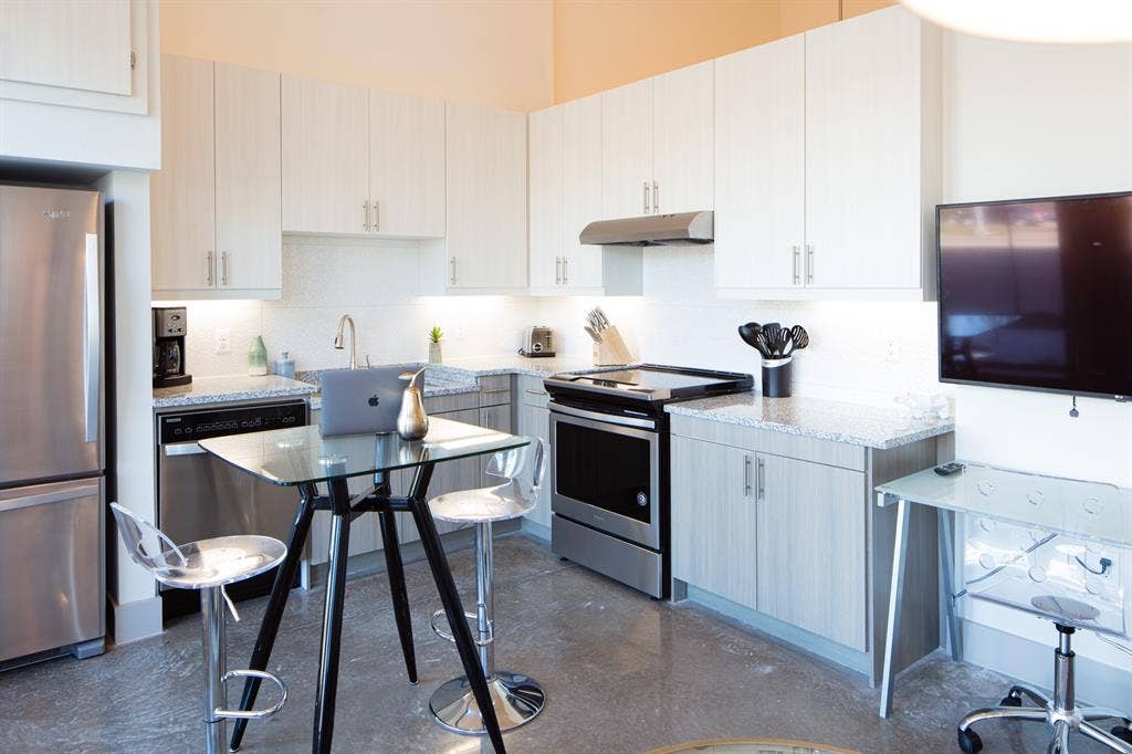 830 N Zang Boulevard, #1117, Dallas, TX 75208 Kitchen with backsplash, white cabinetry, light stone countertops, and appliances with stainless steel finishes