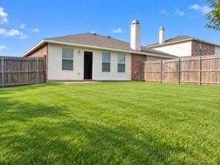 Expansive backyard featuring a manicured lawn, full privacy fencing, and a red brick and siding exterior