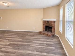 Wood-finish flooring, brick fireplace with a white mantel, and multiple windows with blinds