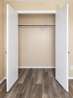 Closet with wood-finish flooring, white bifold doors, and a clothing rod