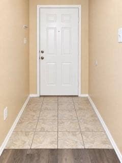 Entryway with tiled flooring, contrasting wood-finish flooring, and a paneled entry door