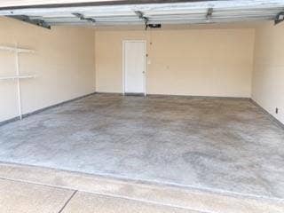 Spacious garage with light-toned walls, a durable concrete floor, and built-in shelving