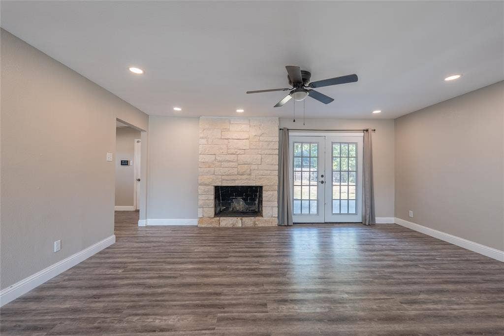 Stone-clad fireplace with a dark firebox, wood-finish flooring, recessed lighting, and a ceiling fan