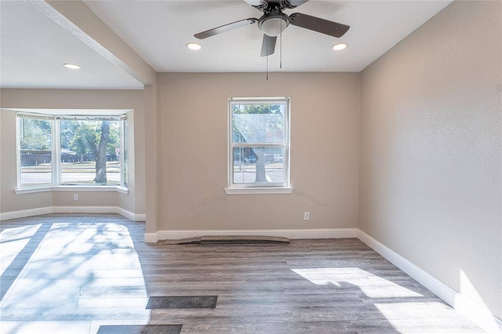 Wood-finish flooring, bay window, recessed lighting, ceiling fan, and neutral wall tones
