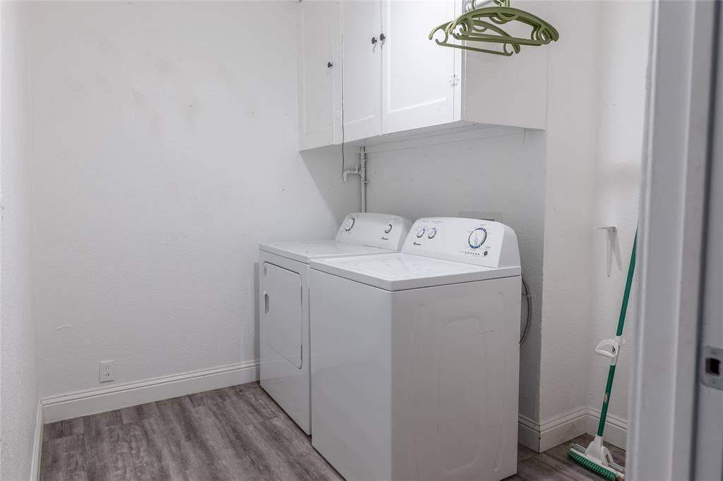 Laundry area featuring wood-finish flooring, white cabinetry, and a utility shelf