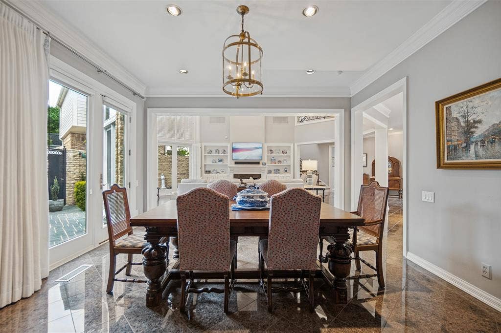 Polished stone flooring, recessed lighting, crown molding, double French doors, and an ornate chandelier