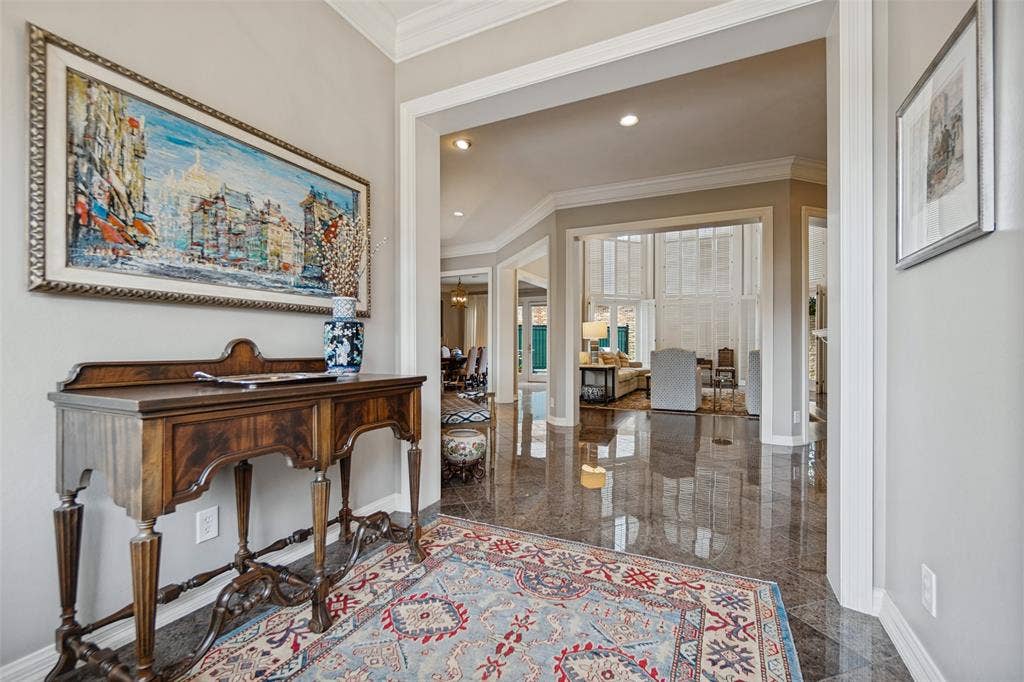 Polished stone tile flooring, high ceilings with crown molding, and an open entryway with arched doorways