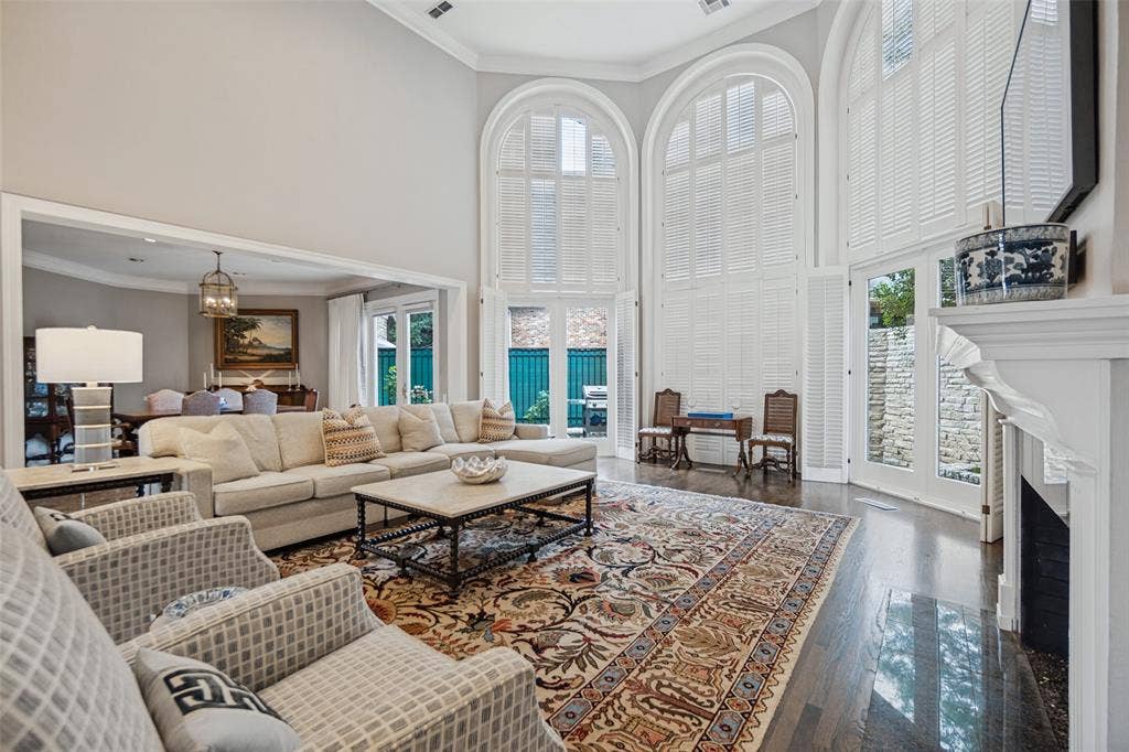 Soaring ceilings, hardwood flooring, fireplace, and arched windows with plantation shutters