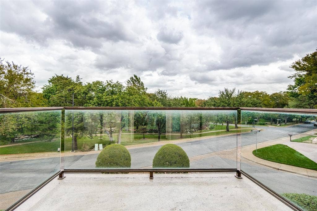 View of greenbelt from office balcony with a glass railing and metal frame