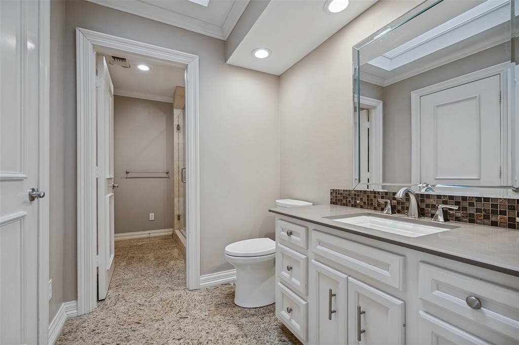 Bathroom with a white vanity, integrated sink, and mosaic tile backsplash