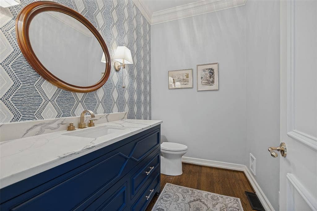 Navy blue vanity with brass hardware, a white countertop, and an undermount sink