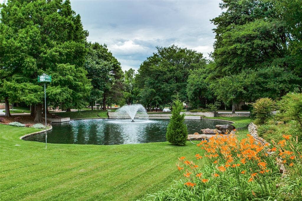 Landscaped pond with an active fountain, surrounded by mature trees and vibrant foliage