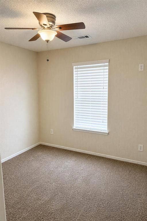Neutral tone wall paint, textured carpet flooring, window with blinds, and ceiling fan with integrated lighting