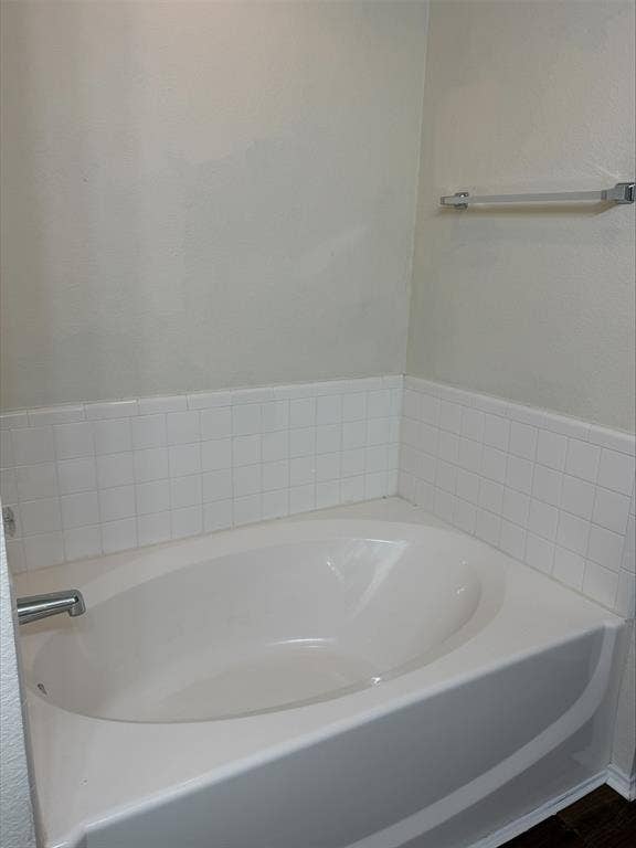 Built-in soaking tub with surrounding white tile wainscoting and chrome fixtures