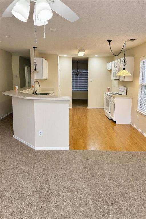 Kitchen with white cabinetry, light-toned countertops, and wood-finish flooring
