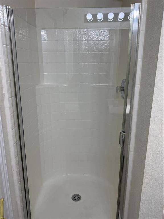 Walk-in shower featuring a chrome showerhead, a built-in seat, and a clear glass enclosure