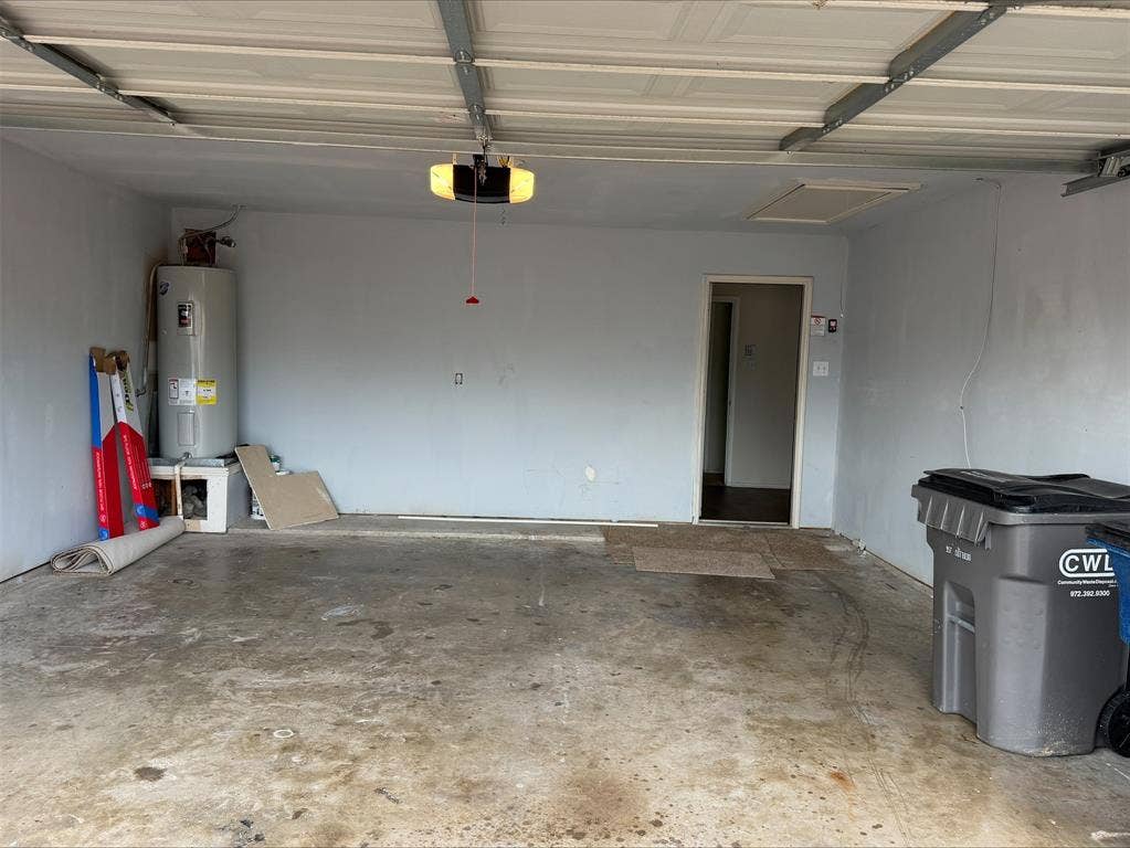 Garage space featuring a water heater, an overhead garage door opener, and a ceiling access panel