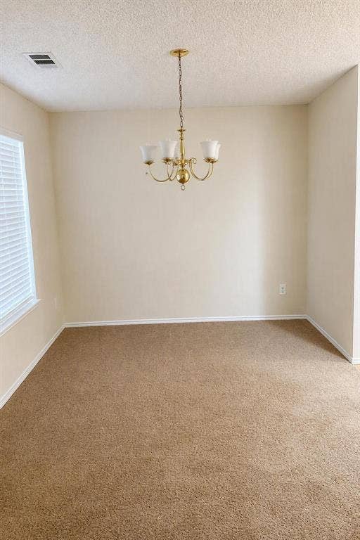Ceiling-mounted chandelier with four frosted glass shades, textured ceiling, light-toned walls, and neutral carpeting