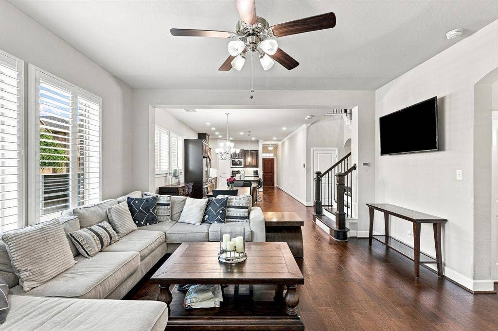 5441 Caine Road, Richardson, TX 75082 Hardwood-finish flooring throughout, ceiling fan with light fixture, custom window shutters, archway details, and staircase with dark wood banister