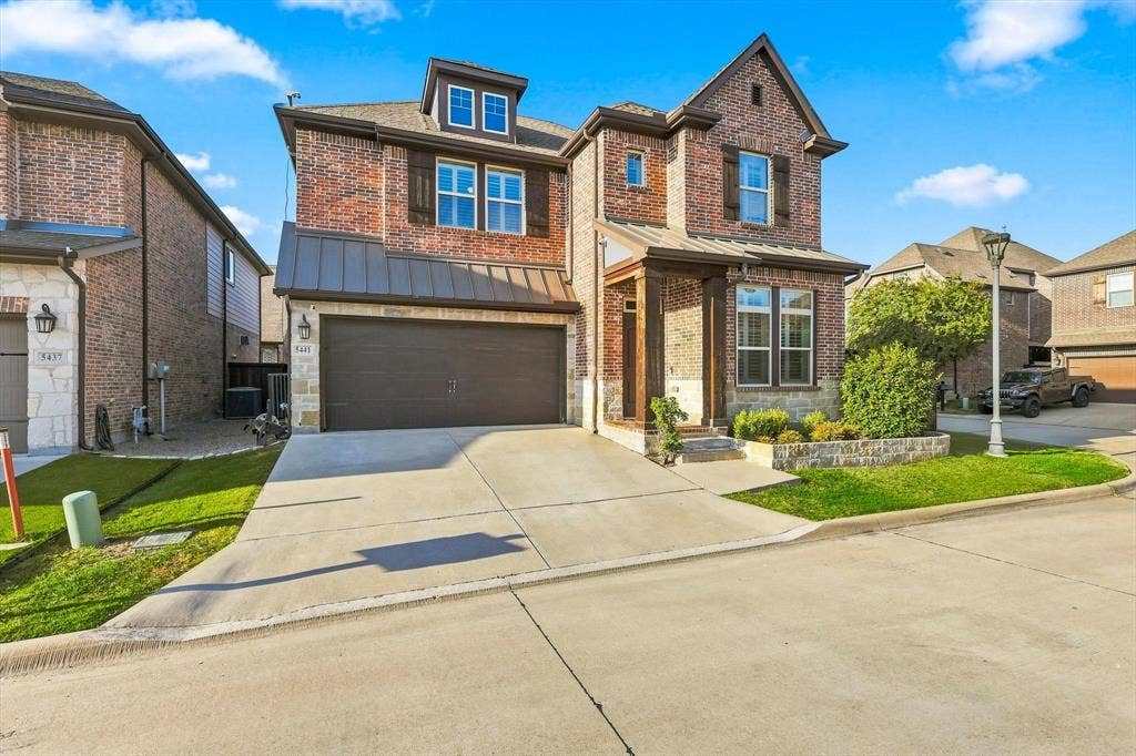 5441 Caine Road, Richardson, TX 75082 Brick and stone exterior with dark trim and shutters, covered entry, attached two-car garage, and a dormer window