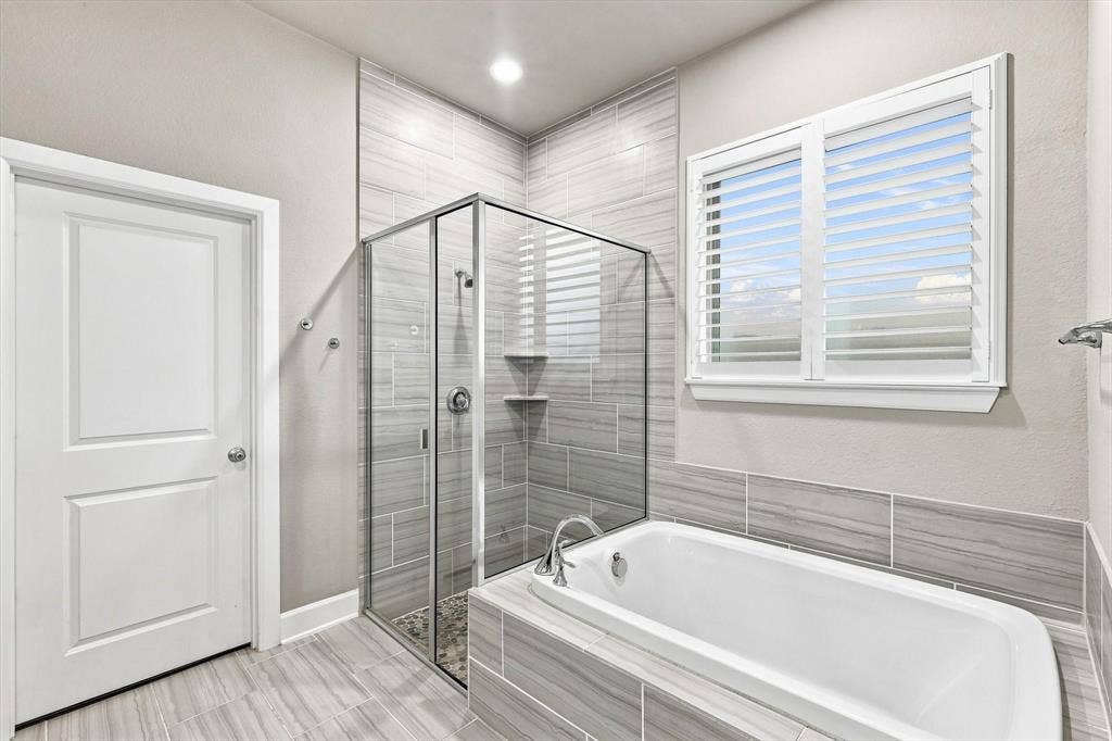5441 Caine Road, Richardson, TX 75082 Built-in bathtub with tiled surround, glass-enclosed shower, wall-mounted showerhead, and tile flooring