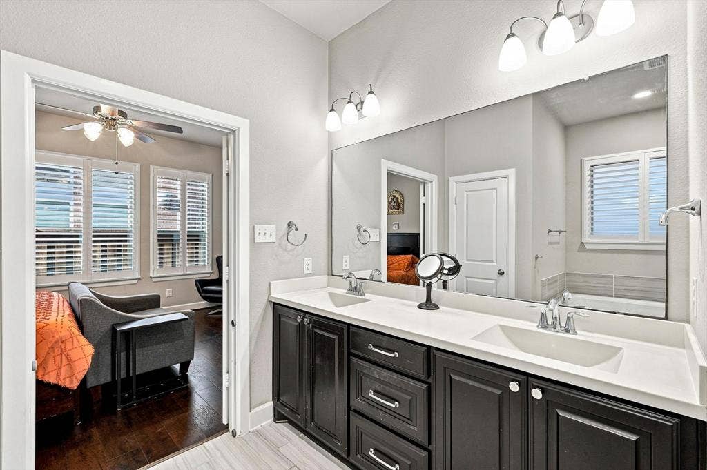 5441 Caine Road, Richardson, TX 75082 Dual vanity with white countertops, dark wood-finish cabinetry, and built-in mirror
