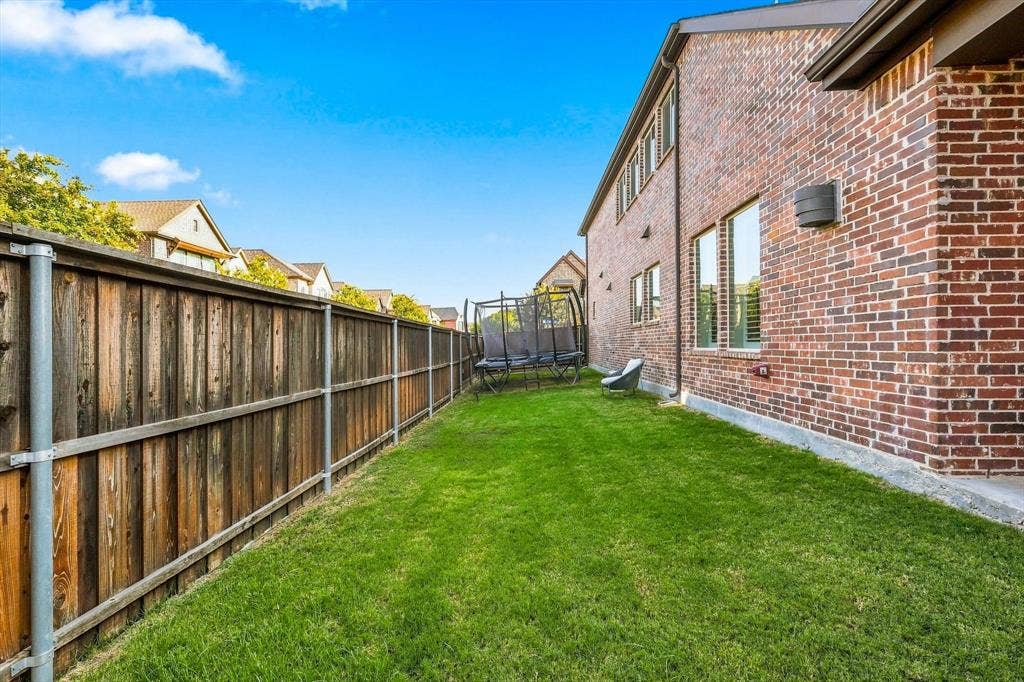 5441 Caine Road, Richardson, TX 75082 Red brick exterior with multiple windows, a wood fence, and a green lawn
