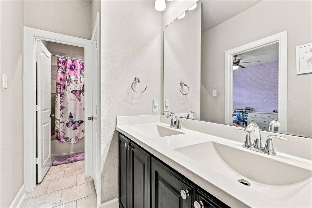 5441 Caine Road, Richardson, TX 75082 Dual vanity with undermount sinks, chrome faucets, and dark cabinetry