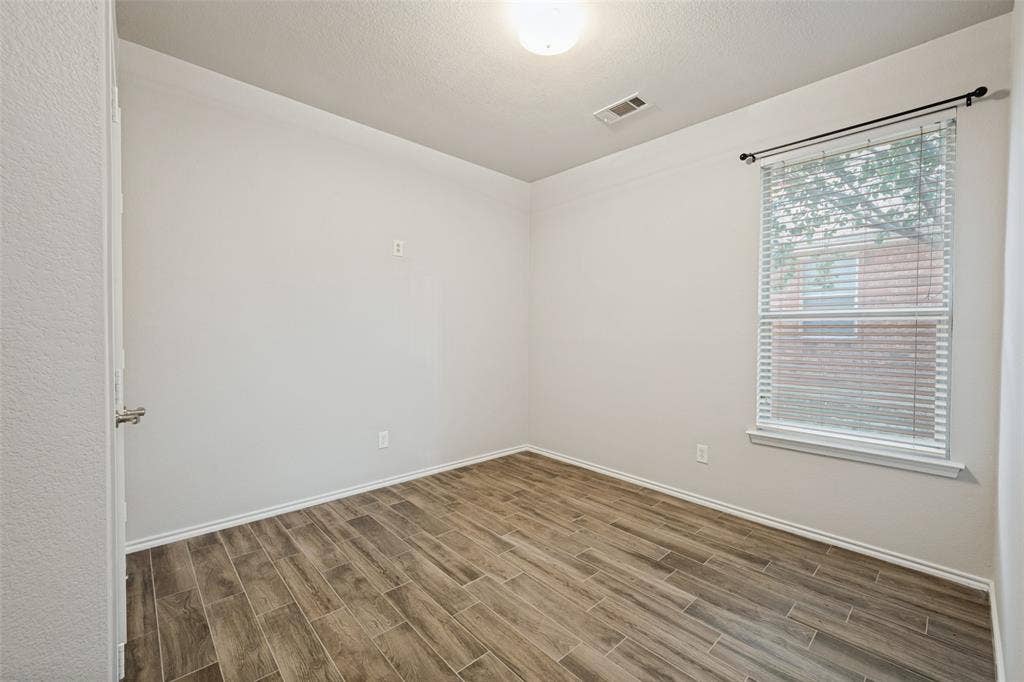 Recessed window with blinds, overhead lighting, wood-finish flooring, and light-toned wall finishes