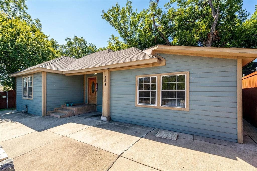 709 S Munger Boulevard, Dallas, TX 75223 Exterior featuring horizontal siding, a composite shingle roof, and a wood-paneled entry door