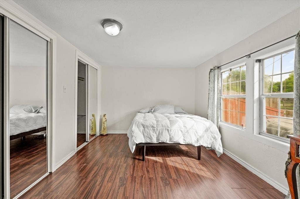 709 S Munger Boulevard, Dallas, TX 75223 Wood-finish flooring, two large windows, overhead flush-mount lighting, and two mirrored sliding door closets