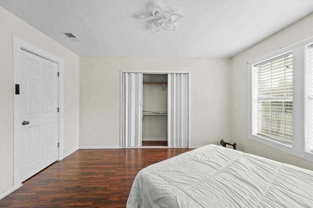 709 S Munger Boulevard, Dallas, TX 75223 Wood-finish flooring, white paneled door, bi-fold closet doors with shelving, white window blinds, and a decorative ceiling fan