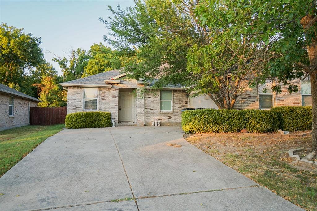 1517 Harvest Crossing Drive, Wylie, TX 75098 Stone veneer exterior with mature trees, concrete driveway, and established shrubbery